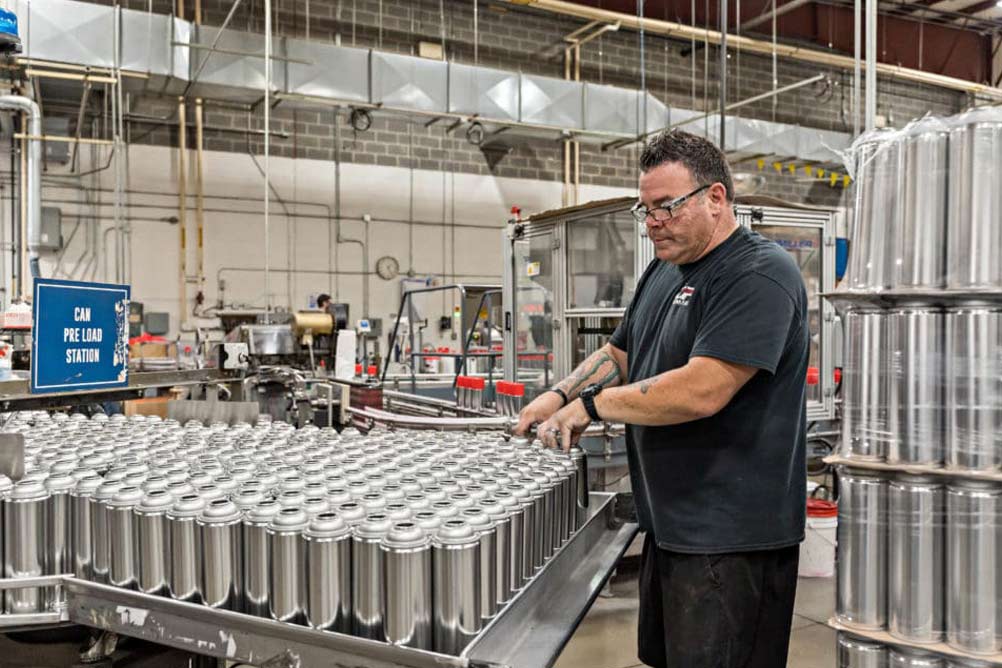 Chem-Pack floor worker inspects cans of product at the warehouse